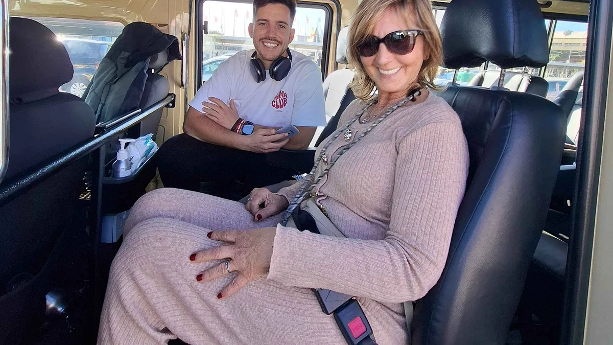 Two smiling travellers sitting inside a safari vehicle before a game drive
